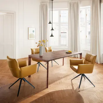 Esszimmer mit Holztisch und gelben Lederstühlen auf Fischgrätparkett.